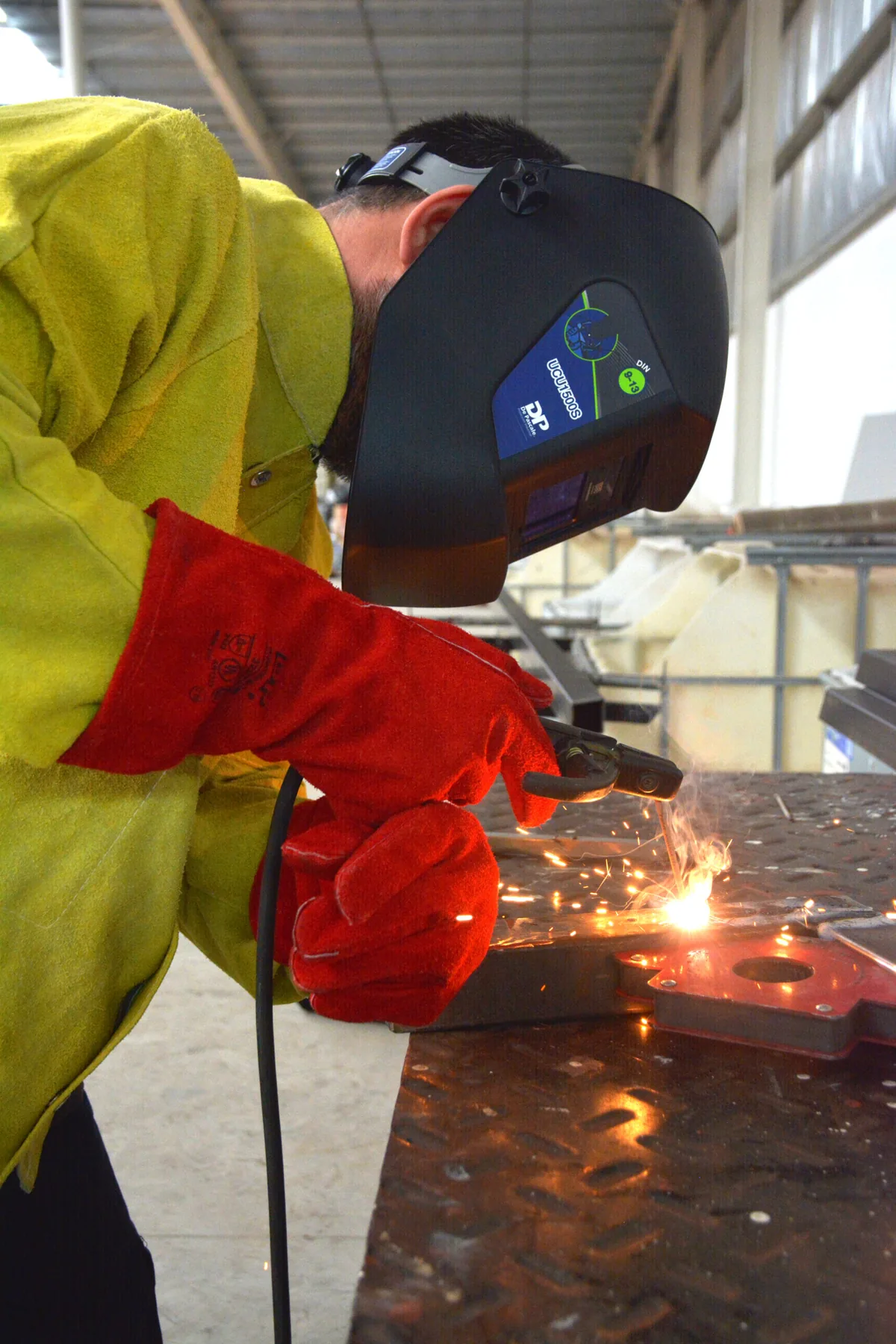 Soldador trabajando con guantes de descarne rojos De Pascale
