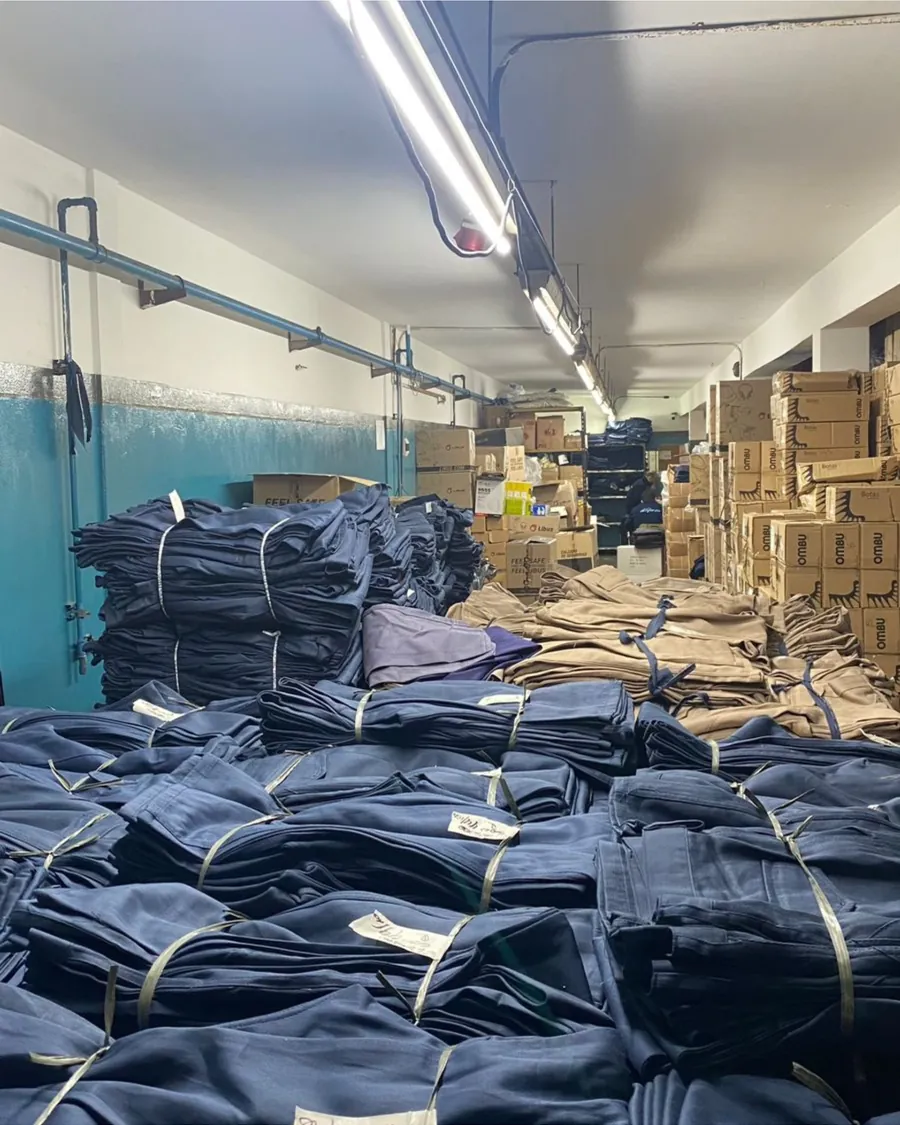 Pantalones y camisas de trabajo apilados en el depósito